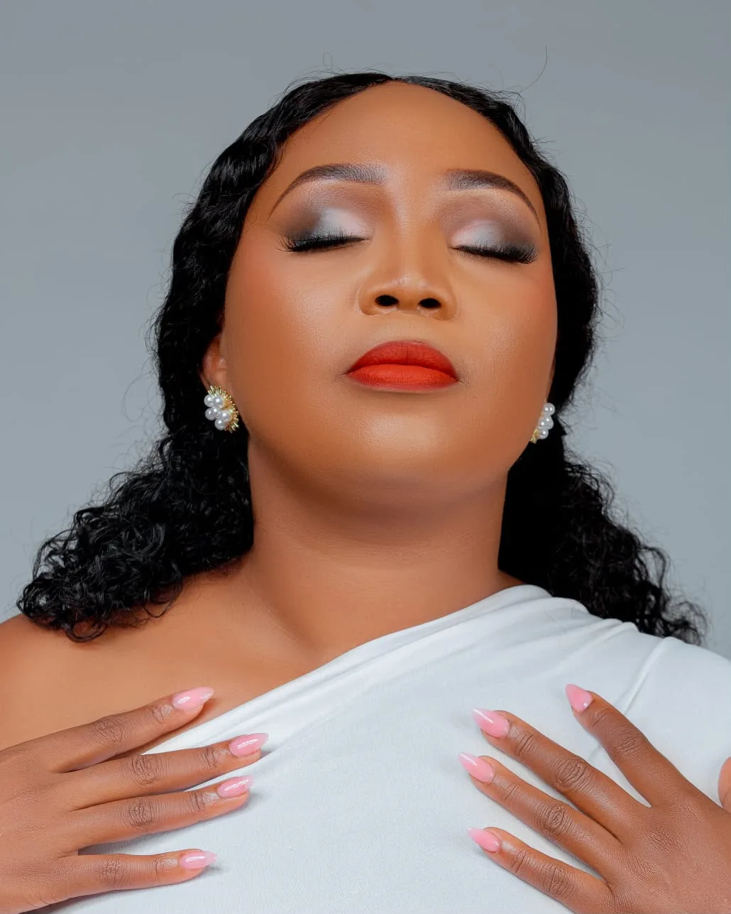 Professional makeup look with pearl earrings and pink nails